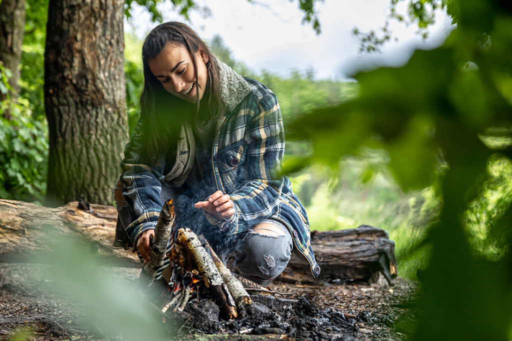 A girl tending a campfire she's built with a fixed blade knife - a great way to spend a day and a perfect tool for the task!